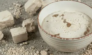 Kostki świeżych drożdży i spieniona masa w misce – to początek, jak zrobić drożdże do pieczenia.