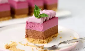 Trójwarstwowe ciasto bez pieczenia z malinową i czekoladową pianką, na kruchym spodzie, ozdobione miętą. Idealne na deser.