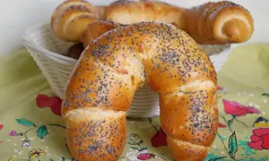 Złocisty rogal z makiem, świeżo upieczony, kusi swoim aromatem. W koszyku czekają kolejne pyszności.