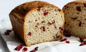 Puszysty chleb z żurawiną, z chrupiącą skórką i widocznymi kawałkami owoców. Idealny na śniadanie.