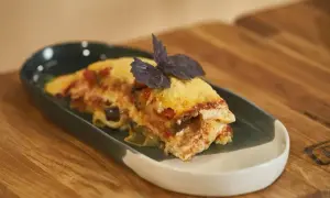 Pyszna lasagne z bakłażanem i pomidorami, udekorowana bazylią. Idealna do podgrzania i szybkiego obiadu.