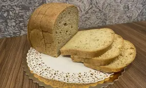 Chleb keto z mąki kokosowej, pokrojony w kromki, prezentuje się apetycznie na złotej podstawce.