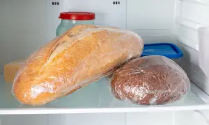 Dwa bochenki chleba, jeden jasny, drugi ciemny, zawinięte w folię spożywczą, leżą na półce lodówki. To może być odpowiedź na pytanie, dlaczego chleb pleśnieje.