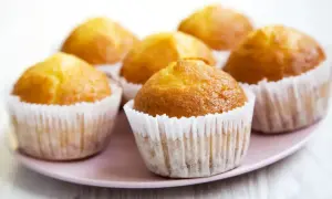 Sześć złotych muffinek w papierowych foremkach na różowej paterze. Idealne na szybki muffinki przepis.