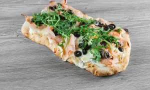 Pyszna pinsa z szynką, mozzarellą, rukolą i oliwkami. Idealny przepis na szybki obiad.