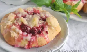 Pyszne drożdżówki z malinami, posypane kruszonką i polane lukrem, kuszą swoim wyglądem i zapachem.