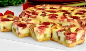 Pyszne ciasto z truskawkami i rabarbarem, pokrojone na kawałki, z kremowym nadzieniem i chrupiącym spodem.