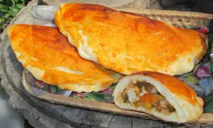 Złociste mini calzone z aromatycznym nadzieniem, ułożone na drewnianej desce.