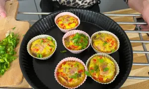 Sześć pysznych muffinek jajecznych z szynką, papryką i szczypiorkiem, gotowych do podania.