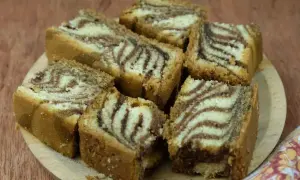 Kawałki ciasta zebra z charakterystycznym wzorem, ułożone na drewnianej desce.