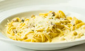 Tagliatelle z grzybami w kremowym sosie, posypane parmezanem. Pyszny sos cebulowy podkreśla smak dania.