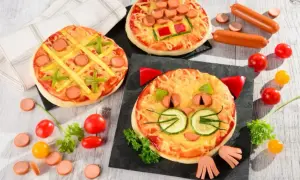 Wesołe pizza dla dzieci: jedna w kształcie kota, druga jak kółko i krzyżyk, trzecia z parówkami i papryką.