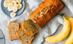 Chlebek bananowy, pokrojony w plastry, z bananami i plasterkami na talerzyku. Kwestia smaku, czy wolisz cały bochenek, czy kawałek.