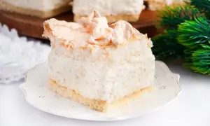 Puszyste ciasto biały michałek z delikatną pianką i bezą, podane na ozdobnym talerzyku.