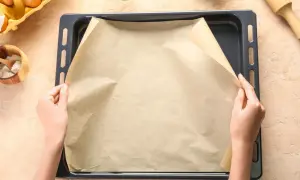 Dłonie układają papier do pieczenia na blasze. Zastanawiasz się, czym zastąpić papier do pieczenia? Oto praktyczne rozwiązanie!