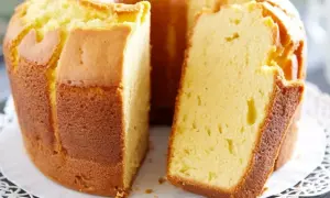 Puszysta babka pomarańczowa, zrumieniona na zewnątrz, z widocznym kawałkiem ciasta. Idealna na popołudniową herbatę.