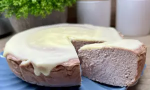 Pyszny sernik z malinami i białą czekoladą, z kawałkiem odciętym do degustacji.