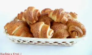 Koszyk pełen pysznych, domowych rogalików z różą, posypanych cukrem. Idealne na deser lub śniadanie.
