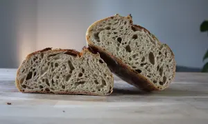 Puszysty chleb żytni, przekrojony na pół, z widocznym, porowatym wnętrzem i chrupiącą skórką.