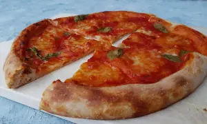 Pyszna pizza na zakwasie z pomidorami i mozzarellą, ozdobiona listkami bazylii. Idealna na każdy dzień.