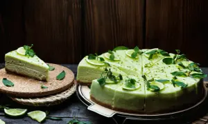 Zielony sernik pistacjowy, udekorowany plasterkami limonki i miętą, wygląda apetycznie.