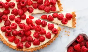 Pyszna tarta z malinami, udekorowana świeżymi owocami, kusi kremowym nadzieniem i chrupiącym spodem. Idealna na deser!