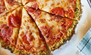 Pyszna pizza na spodzie z kalafiora z serem i pepperoni, pokrojona na kawałki.