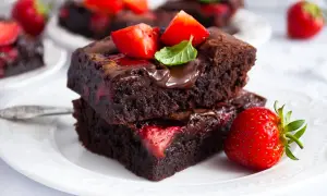 Pyszne brownie z truskawkami, polane czekoladą i ozdobione listkiem mięty. Idealne na deser!