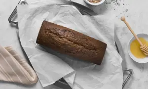 A pyszny, domowy chleb czekoladowy na tacy, obok miseczki z miodem i nasionami.