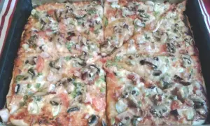 Pyszna pizza na grubym cieście z pieczarkami, pomidorami i papryką, prosto z blachy. Idealna na rodzinny obiad.