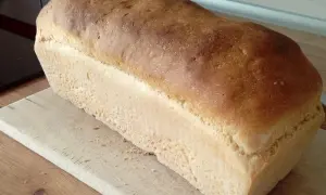 Puszysty chleb na suchych drożdżach, z chrupiącą skórką, leży na drewnianej desce. Idealny do kanapek.