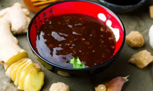 Miseczka z sosem teriyaki, obok świeży imbir, czosnek i cukier. Idealne składniki do sosu teriyaki przepis.