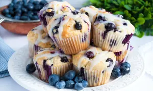 Stos pysznych muffinek z borówkami, polanych lukrem, ozdobionych świeżymi borówkami. Idealne na śniadanie lub deser.