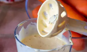 Kremowy majonez powstaje w szklanym naczyniu, gdy blender zanurza się w jego gładkiej masie. Idealny majonez przepis w zasięgu ręki.