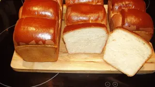 A fresh batch of chleb hokkaido, golden brown and fluffy, awaits. Two loaves are sliced, revealing their soft, airy crumb.