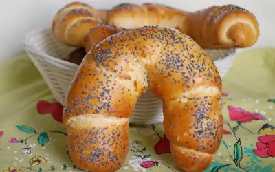 Złocisty rogal z makiem, świeżo upieczony, kusi swoim aromatem. W koszyku czekają kolejne pyszności.