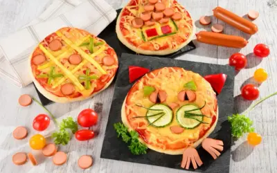 Wesołe pizza dla dzieci: jedna w kształcie kota, druga jak kółko i krzyżyk, trzecia z parówkami i papryką.