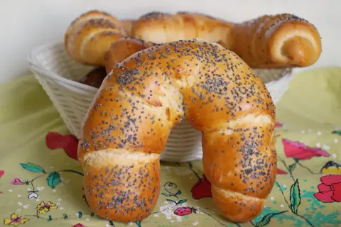 Złocisty rogal z makiem, świeżo upieczony, kusi swoim aromatem. W koszyku czekają kolejne pyszności.