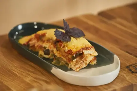 Pyszna lasagne z bakłażanem i pomidorami, udekorowana bazylią. Idealna do podgrzania i szybkiego obiadu.