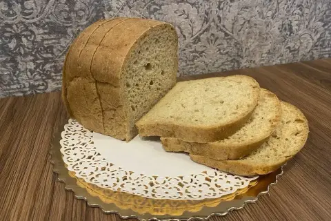 Chleb keto z mąki kokosowej, pokrojony w kromki, prezentuje się apetycznie na złotej podstawce.