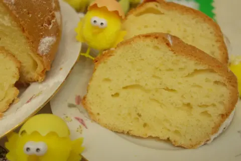 Puszysta babka majonezowa, pokrojona na plastry, z ozdobnymi kurczaczkami wielkanocnymi.