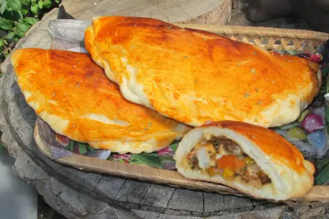 Złociste mini calzone z aromatycznym nadzieniem, ułożone na drewnianej desce.