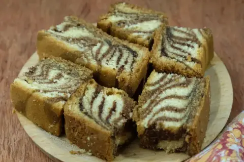 Kawałki ciasta zebra z charakterystycznym wzorem, ułożone na drewnianej desce.