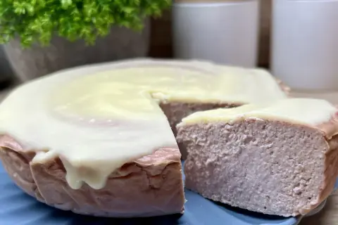 Pyszny sernik z malinami i białą czekoladą, z kawałkiem odciętym do degustacji.