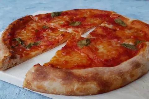 Pyszna pizza na zakwasie z pomidorami i mozzarellą, ozdobiona listkami bazylii. Idealna na każdy dzień.