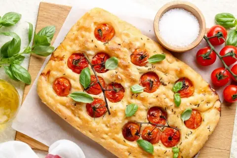 Pyszna focaccia z pomidorkami koktajlowymi i bazylią, idealna do pesto.