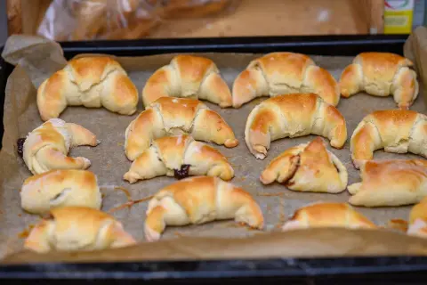 Szybkie rogaliki kruche, lekko zarumienione, ułożone na blasze wyłożonej papierem do pieczenia. Niektóre z nadzieniem.