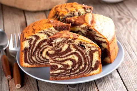 Pyszna babka marmurkowa z czekoladowymi i waniliowymi wzorami, pokrojona na talerzu, gotowa do degustacji.