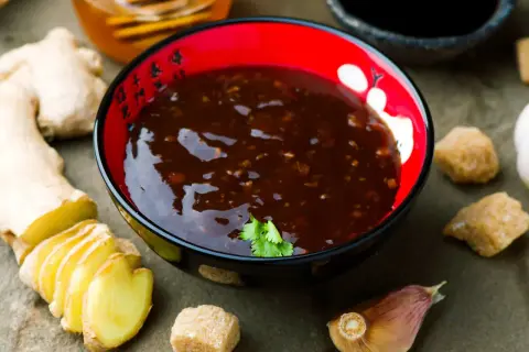 Miseczka z sosem teriyaki, obok świeży imbir, czosnek i cukier. Idealne składniki do sosu teriyaki przepis.