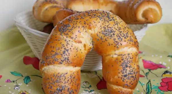 Złocisty rogal z makiem, świeżo upieczony, kusi swoim aromatem. W koszyku czekają kolejne pyszności.